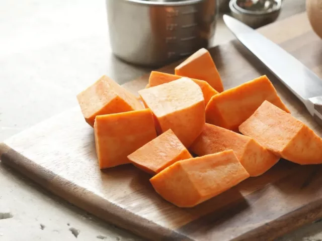 Diced yams on wooden cutting board to make a fall recipe for radiant skin