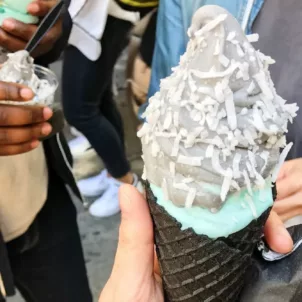 Grey goth ice cream with toppings in a black cone