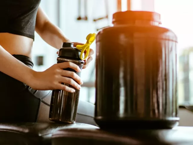 Woman making a protein shake to go to complement her workout