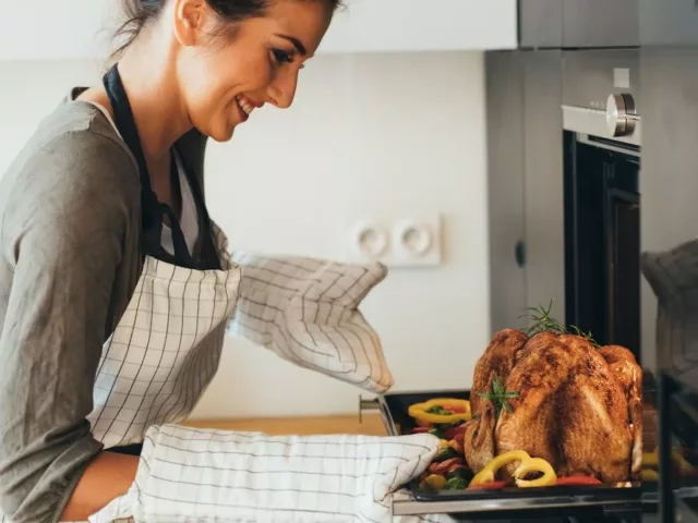 Young woman taking dinner out of the oven