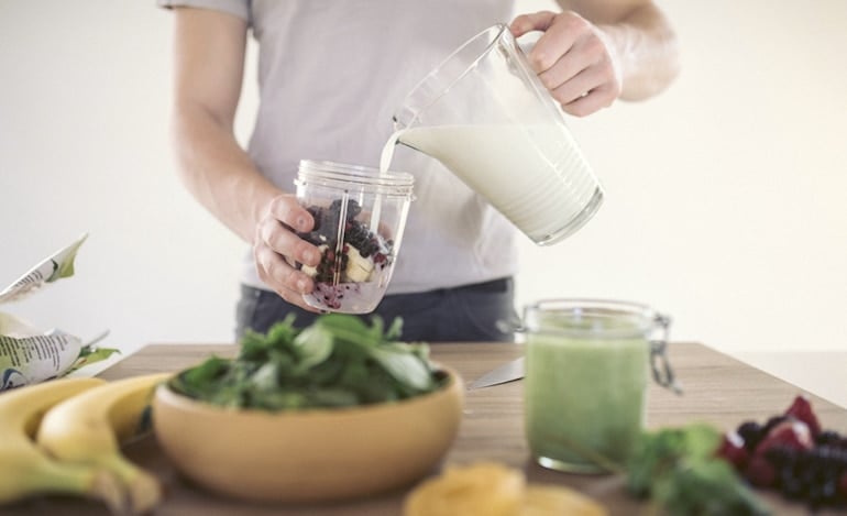 Man pouring milk into a smoothie