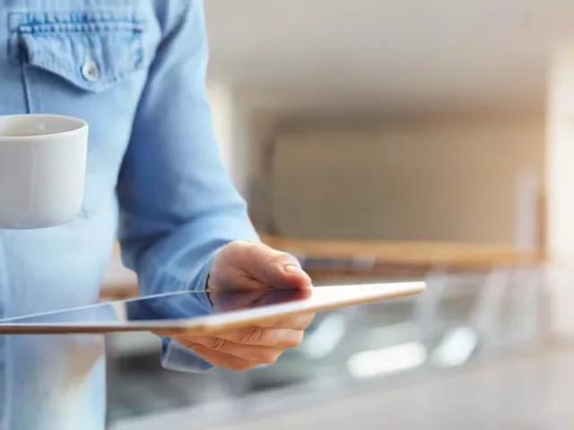 Man reading the news on tablet while drinking coffee