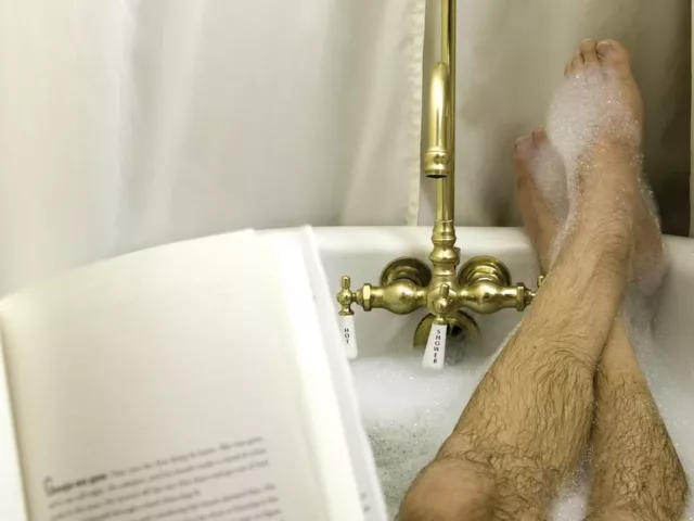 Man reading in bathtub to illustrate self-care for men ideas