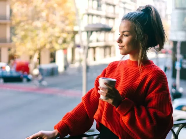 Woman enjoying coffee on her balcony, observing nature and the benefits of staying present