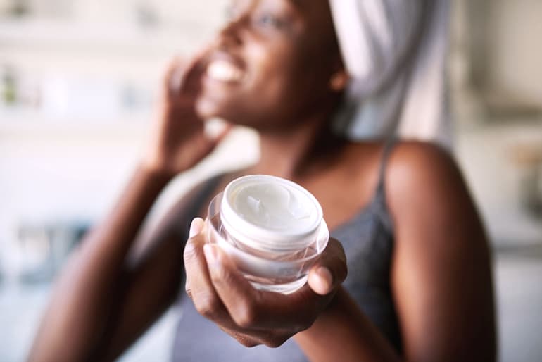 Woman using exfoliating topical products to treat and heal her acne scars